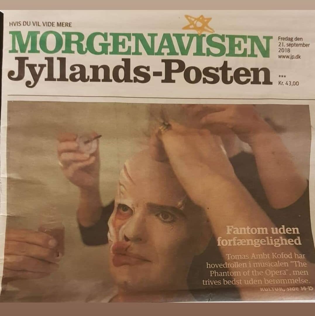 Avisforside med teatermakeup hvor en performer får påsat maske og scenemakeup