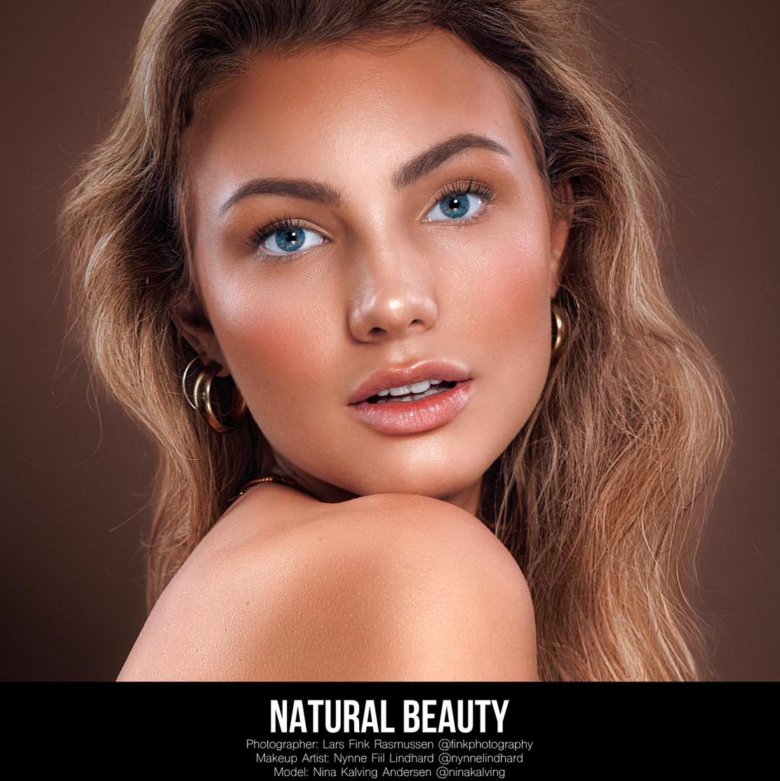 kvinde med naturlig glød, blød bronzemakeup, lys blå øjenfarve og løse bølger i håret