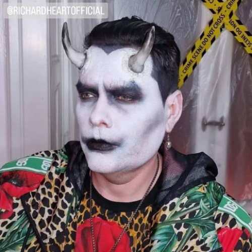 mand med hvid-sorthalloween makeup, sorte læber, mørke øjne og små horn