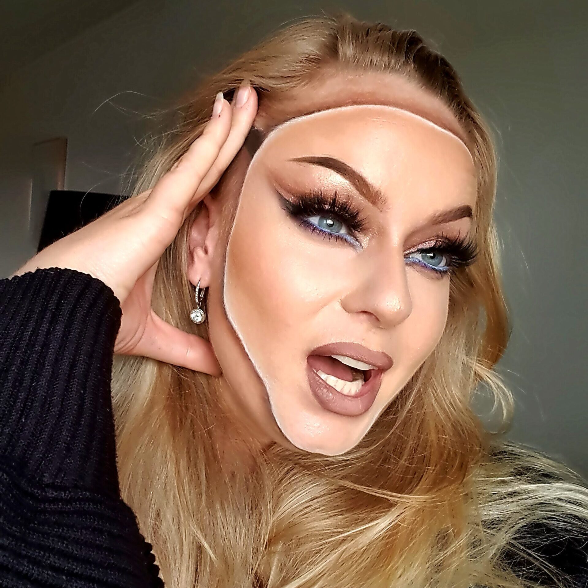 kvinde med illusion makeup, hvor ansigtets omrids er tegnet uden på huden, dramatisk øjenmakeup og langt blond hår