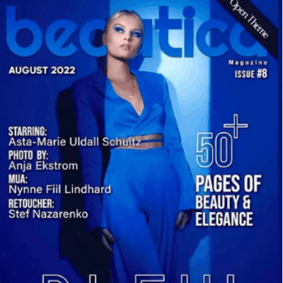 kvinde i blå kjole med sleek opsat hår, dramatisk øjenmakeup og editorial lyssetting på magasinforside