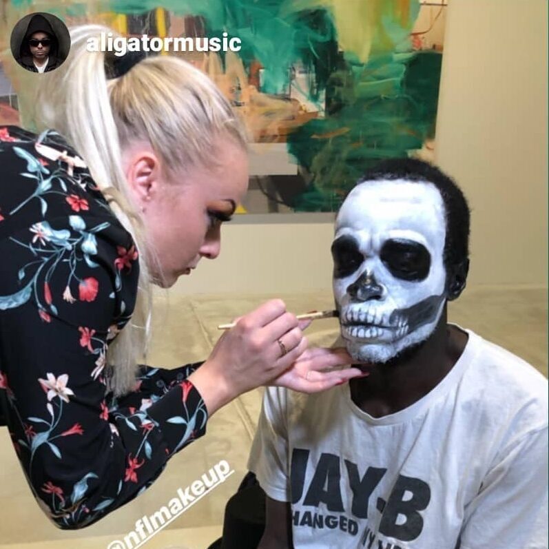 makeupartist laver hvid-sort skelet ansigtsmaling på mand, der sidder på stol