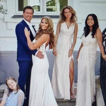 Brudepar og brudepiger i hvide kjoler; bruden med glam makeup og løse bølger i håret.