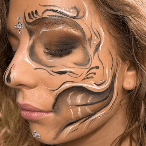 Kreativ facepaint med smokey eye og kunstneriske sorte og hvide linjer omkring øjet.